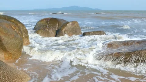 Sea waves washing over large boulders along coastal beach Vídeo Stock 342460472
