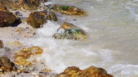 Sea waves washing over reef rocks with splashing spray and white foam on beach Video stock 342328304