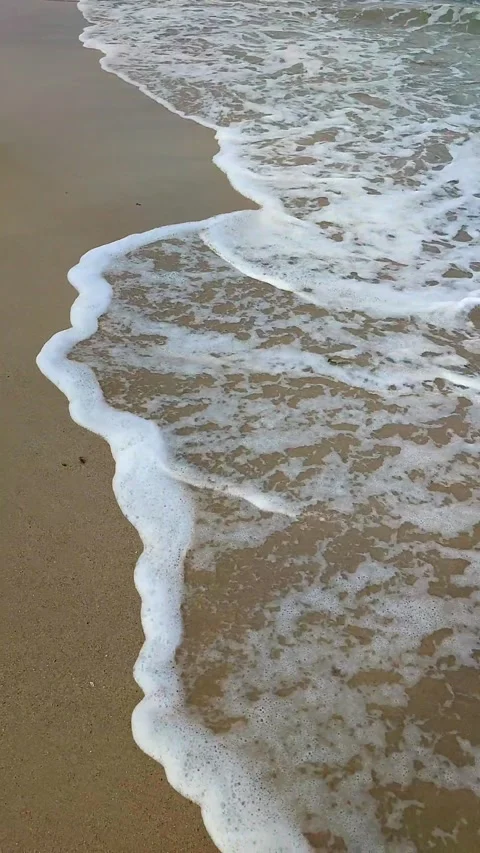 Sea waves with white foam roll on the sandy beach of the seashore close-up. Stock Footage 214623815