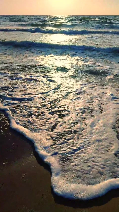 Sea waves white foam rolling onto sandy beach shore. Clean blue water Vertical Stock Footage 305865564