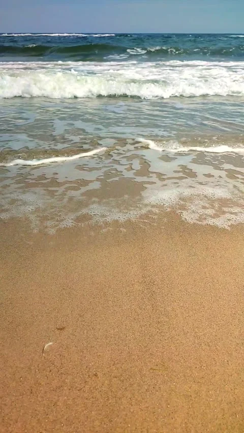 Sea waves white foam rolling onto sandy beach shore. Clean blue water Vertical Stock Footage 305865655