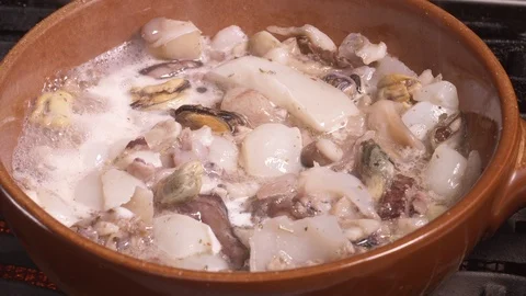 Seafood chowder boiling in a clay pan in UHD Stockbeeldmateriaal 94661173