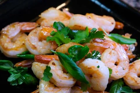 Seafood meal cooking. Mediterranian food recipe. Shrimps frying in pan using Stock Photos