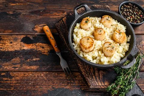 Seafood Risotto with Scallops in a pan. Dark wooden background. Top view. Copy Stock Photos