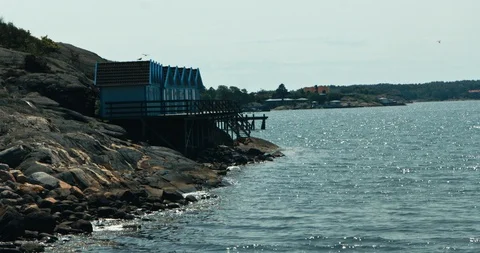 Seagulls fly over small cabins overlooking the sea 스톡 동영상 113948469