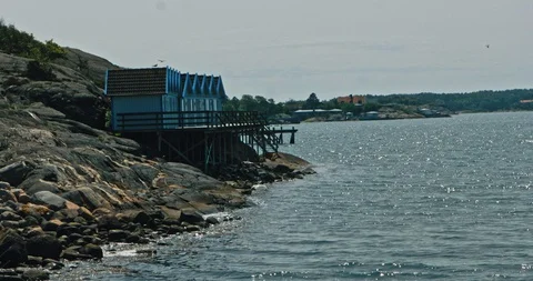 Seagulls fly by some cabins overlooking the sea of the Swedish archipelago 스톡 동영상 113944329