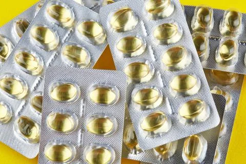 Sealed packages with transparent capsules on yellow background Stock Photos