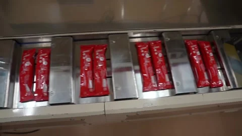 Sealed red pouches lying in shallow metal trays as they advance through a dim Stock Footage 342319400