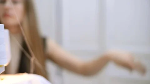 Seamer runs the white thread from the spool into the sewing machine Stock Footage 74161092