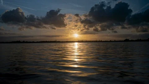 Seamless cinemagraph loop - The sun sets over a lake with dark clouds Stock Footage 114755891