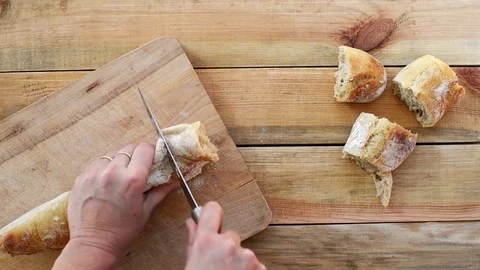 Seamless loop - Cutting bread on a wooden table, view from above Stock Footage 73230418