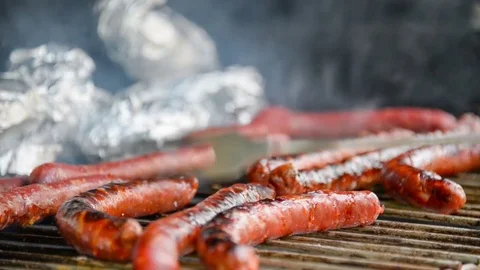 Seamless loop - Fork turning over tasty juicy sausages grilling on a barbecue Stock Footage 76598941