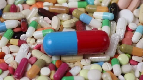 Seamless loop of rotating blue and red pill on pile of pills Stock Footage 280677603