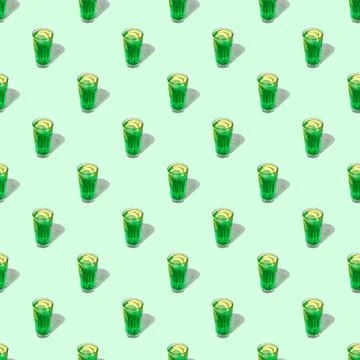 Seamless looping pattern with a transparent glass of green drink on a pastel  写真素材