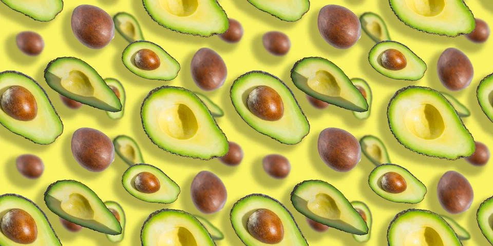 Seamless pattern of avocado fruit halves and bones isolated on yellow background Stock Photos