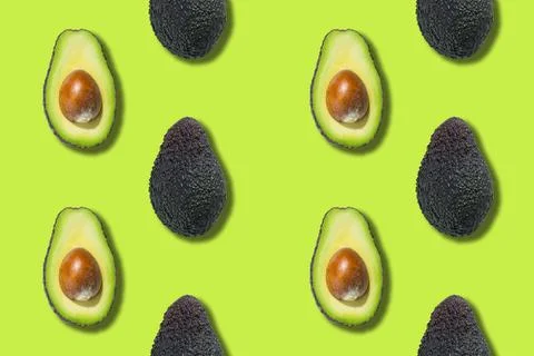 Seamless pattern of avocado halves isolated on green background. Top view Stock Photos
