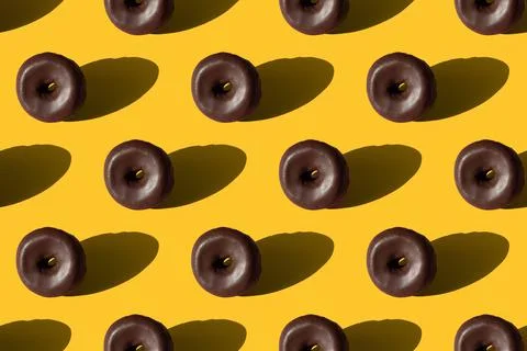 Seamless pattern of chocolate glazed donuts on a yellow background Fotos de archivo