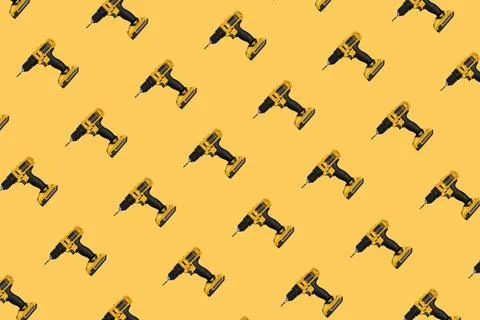 Seamless pattern. Cordless electric yellow screwdriver on a yellow background. Stock Photos