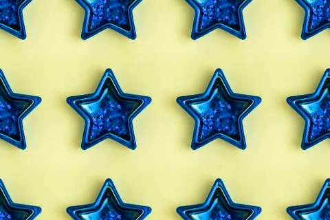Seamless pattern from five pointed blue metallic star on yellow surface. Stock Photos