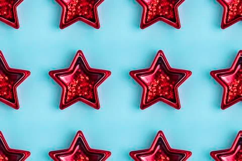 Seamless pattern from five pointed red metallic star on pastel blue surface. Stock Photos