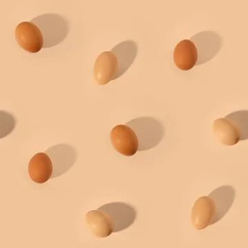 Seamless pattern with fresh beige chicken eggs on peach background 스톡 사진