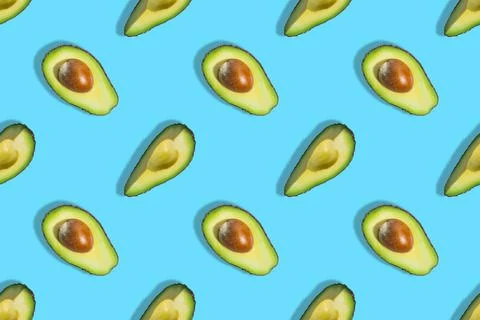 Seamless pattern of fresh green avocado fruit half isolated on blue background Stock Photos