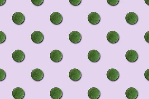 Seamless pattern of green chlorella or spirulina tablets on a pink background Stock-Fotos