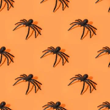 Seamless pattern of Halloween spiders, fun decoration on orange background. Stockfoto's