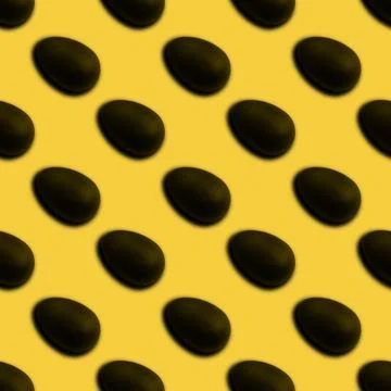Seamless pattern of halves of black chocolate Easter eggs on a yellow backgro Stock Photos