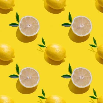 Seamless pattern with lemon cut and whole with leaves on a yellow background Stock Photos