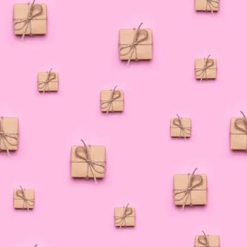 Seamless pattern made of gift wrapped in kraft paper on a pink background. Stock Photos