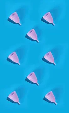 Seamless pattern of a pink menstrual cup on a blue background. Stock Photos
