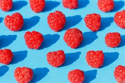 Seamless pattern of raspberries on a blue background close-up. Stock Photos