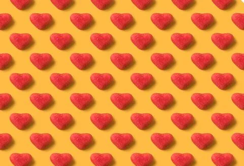 Seamless pattern of red gummy hearts on light yellow background Stock Photos
