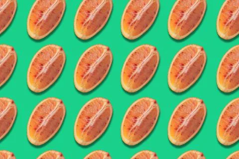 Seamless pattern of red orange slices on green background, abstract citrus ba Stock Photos