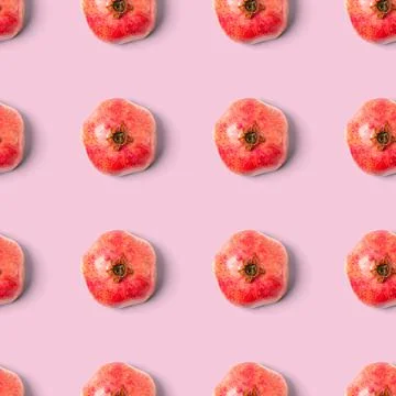 Seamless pattern with red pomegranate fruit on pink background. Minimal flat lay Stock Photos