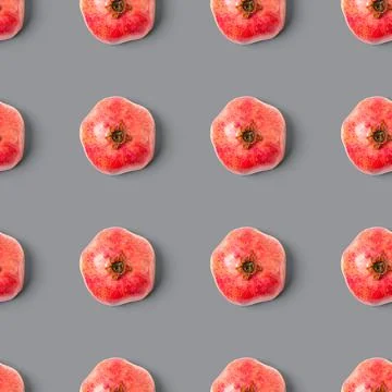 Seamless pattern with red pomegranate fruit on grey background. Minimal flat lay Stock Photos