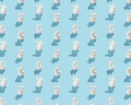 Seamless pattern of white ceramic bunnies with shadows on a light blue backgr Stock Photos