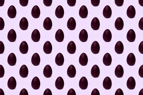 Seamless pattern of whole chocolate Easter eggs on a purple background, tinte Stock Photos