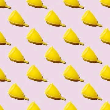 Seamless pattern of yellow menstrual cups isolated on a pink background. Wome 스톡 사진