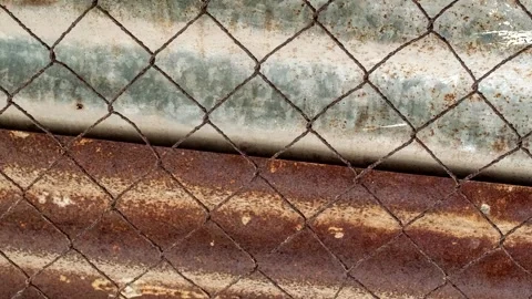 Seamless rotating loop of a weathered wire mesh fence overlaying rusty corr.. Stock-Footage 343513209