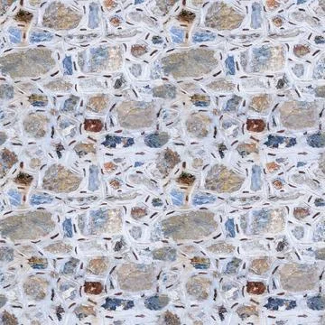 Seamless texture of wall made of multicolored stones. Asymmetric masonry. Stock Photos
