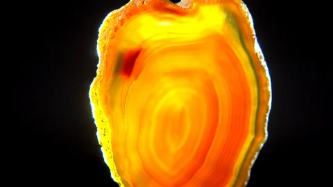 Seamlessly rotating an orange mineral (Agate) in front of black background Stock Footage 104594079