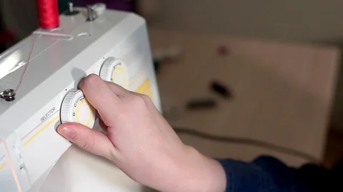 The seamstress chooses the mode on the sewing machine. She rotates the switch 库存影片 101869479