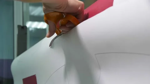 Seamstress cuts paper with sewing pattern for hockey uniform Stock Footage 142800941