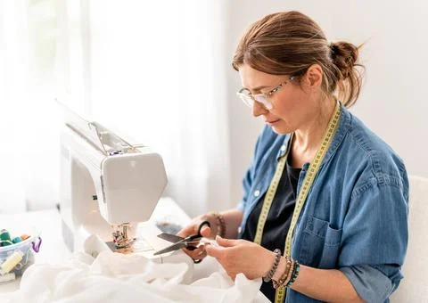 Seamstress cuts thread while sewing in studio Stock-Fotos