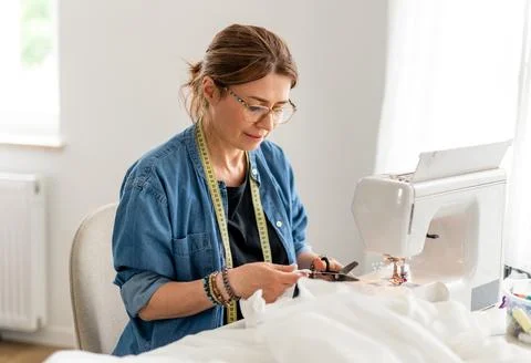 Seamstress cuts thread while sewing in studio Stock-Fotos