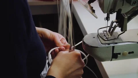 Seamstress cuts threads on sewed laces near machine tool Stock Footage 236908637