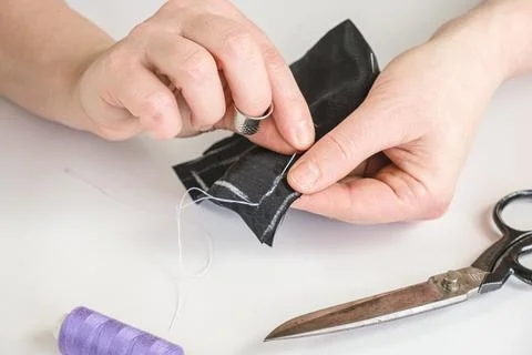Seamstress does running stitch a pattern pieces of clothing Stock Photos