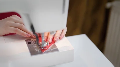 Seamstress is doing stitch on a small red piece of fabric by sewing machine Stock Footage 82531670